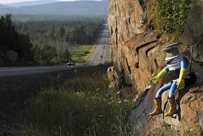 The hitchBOT is seen posed next to Highway 17 north of Sault Ste. Marie, Ontario, and a portion of the Trans-Canada Highway on Aug. 5, 2014.