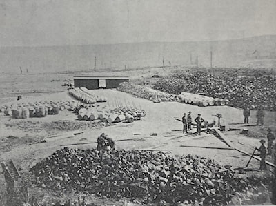 Loading matte at the East Smelter yard in Copper Cliff. The copper-nickel matte was brought from the smelter in portable moulds, broken up, loaded into barrels, weighed, and shipped to the refinery, located at the time in Bayonne, New Jersey. (c.1890s)